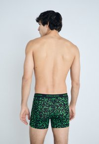 Boxer shorts with a black base featuring a green wavy pattern. The waistband displays "BJÖRN BORG" in contrasting color.