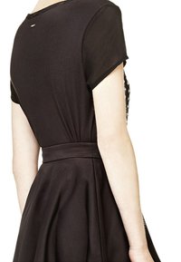 Vestido negro con mangas cortas, un corpiño ajustado y una falda acampanada. Tejido suave con una cintura ceñida, que presenta un sutil detalle en la parte posterior.