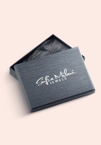Grå smykkeboks med en tekstureret overflade, der har et hvidt logo "Sofia Milani JEWELS" på låget og sort silkepapir indeni.