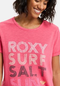 Pink cotton t-shirt med lagdelt tekstdesign i sort, hvid og guld. Rund hals, korte ærmer, blød tekstur og afslappet pasform.