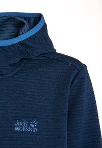 Mörkblå fleecetröja med texturerad design, hög krage och ljusblå kant. Har en broderad logotyp i nedre vänstra hörnet.