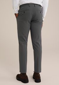 Szürke, slim-fit nadrág, két hátsó zsebbel és gombos zárással. Zsírmentes, könnyű anyagból készült. Barna lábbelivel párosítva.