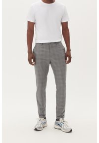 Grå rutiga byxor i lätt material, med en platt front och slim fit, tillsammans med en enkel vit t-shirt och sneakers.