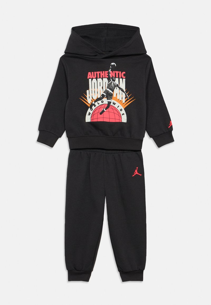 Μαύρη φόρμα με hoodie και παντελόνι φόρμας, που χαρακτηρίζεται από μια μεγάλη γραφιστική εκτύπωση με μπασκετμπολίστα, ενισχυμένη με κόκκινες λεπτομέρειες λογότυπου. Ψηφιακό ύφασμα, άνετος σχεδιασμός.