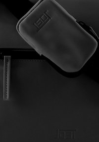 Borsa nera con una texture liscia, dotata di chiusura a zip e una pochette removibile. Logo in rilievo discreto su entrambe le superfici principale e della pochette.