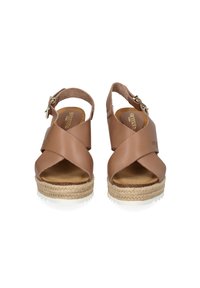 Brown leather sandals with a crisscross design, open toe, ankle strap, and woven jute-style platform sole with white trim. Buckle detail included.
