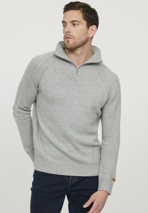 Pull en maille gris avec col montant, demi-zip et ourlet côtelé. Présente des manches raglan et une texture fine, idéal pour le superposition.