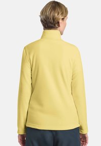Gelbes Fleece-Pullover mit hohem Kragen, langen Ärmeln und glatter Textur. Einfaches Design, keine sichtbaren Muster oder Akzente.