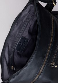 Black leather handbag with a zipper opening, featuring a smooth exterior, interior pocket, and subtle black lining detail.