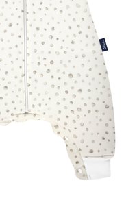 Helles Creme-farbenes Stoff-Jackett mit grauen Punkten, ausgestattet mit Druckknöpfen am Saum und gerippten weißen Bündchen. Weiche Textur.