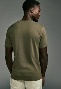 Olivgrünes kurzärmliges T-Shirt mit Rundhalsausschnitt, aus einem weichen, glatten Stoff; taillierte Form und minimale Nähdetails.