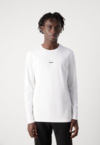 T-shirt de manga longa branca feito de algodão suave, apresentando um pequeno logotipo preto "BOSS" no peito e um decote redondo.