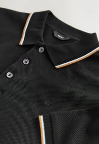 Schwarzes gestricktes Poloshirt mit strukturierter Oberfläche, drei Knöpfen und einem Kragen mit orangefarbenen und hellblauen Streifen. Dezentes Logodetail.