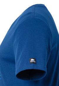 Camiseta de manga corta azul con una textura de algodón suave. Presenta un cuello redondo y una etiqueta negra con "FORSBERG" en la manga.