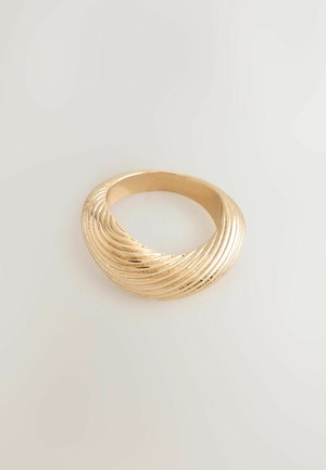 Gold ring with a twisted, ribbed design resting on a plain light background.
