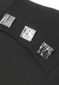 Tissu noir avec texture côtelée, comportant trois accents métalliques carrés avec une surface texturée. Le design est épuré et moderne.