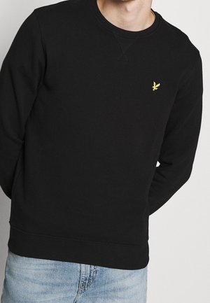 Sweatshirt noir en mélange de coton avec un col ras du cou, des poignets et un ourlet côtelés. Présente un petit logo jaune sur la poitrine.