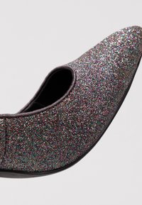 Chaussure à bout pointu scintillante avec une base noire, ornée de paillettes multicolores et d'une texture lisse. Design découpé au cou-de-pied.