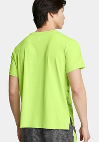 Camiseta atlética de manga corta en un brillante verde lima, con un respaldo texturizado que presenta pequeñas perforaciones y una abertura lateral para mejorar la transpirabilidad.