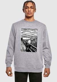 Szürke pulóver, amelyen Edvard Munch "A kiált�ás" című művének fekete-fehér változata látható, középen kiemelve. Puha anyag, laza szabással.