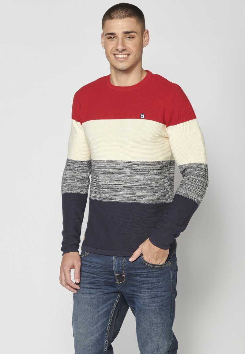 Maglione lavorato a maglia con strisce orizzontali rosse, crema, grigie e navy. Collo rotondo, texture a costine e un piccolo logo sul petto.