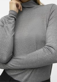 Haut à col roulé gris à manches longues avec un design texturé côtelé. Le tissu présente des accents de brillance subtile et des manches ajustées.