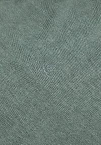 Groene gebreide trui met een subtiele borduursel van een schedel en gekruiste botten. Gemaakt van zachte stof met een textuurpatroon.