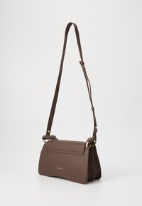 Brown leather crossbody bag with a pebbled texture, flat flap closure, adjustable strap, and gold-tone hardware accents.