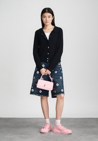 Melna ribota kardigāna ar zelta pogām, džinsa svārki ar baltu ziedu izšuvumu, rozā ādas rokassoma un rozā kedas.