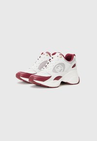 Sneaker bianco e bordeaux con pannelli in rete, punta rotonda e suola texturizzata. Presenta occhielli dorati e un logo prominente sul lato.