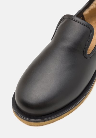 Must musta slip-on kingad ümarate varvastega ja kontrastse beeži kummitaldaga. Ei sisalda nähtavaid metallosi ega mustreid.