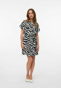 Abito a camicia in stampa zebra bianca e nera, con maniche corte, vita con cintura e vestibilità rilassata. Tessuto morbido e lunghezza al ginocchio.