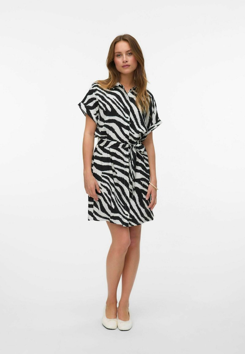 Abito a camicia in stampa zebra bianca e nera, con maniche corte, vita con cintura e vestibilità rilassata. Tessuto morbido e lunghezza al ginocchio.
