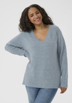 Light blue v-neck sweater with long sleeves, soft texture, ribbed cuffs, and a relaxed fit. Paired with light blue jeans.