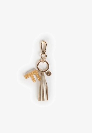 Portachiavi con una lettera "T" in glitter oro, un pon-pon in pelle beige e una clip in metallo dorato; presenta un anello rotondo e un ciondolo con logo.
