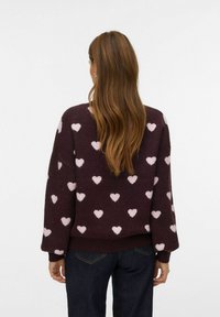 Pull en maille bordeaux foncé avec des motifs de cœurs rose clair. Caractérisé par une coupe décontractée, des poignets côtelés et un col rond.