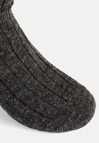 Calzino grigio lavorato a maglia con motivo a coste testurizzato, punta arrotondata, che mostra le fibre in tutta la sua superficie, caratterizzato da un aspetto morbido e accogliente.