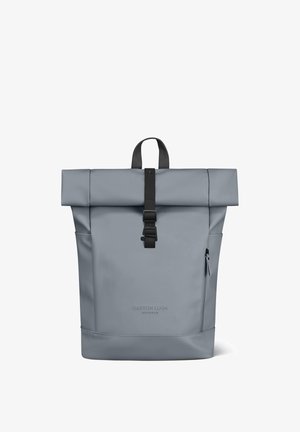 Grijze roll-top rugzak met zwarte gespband, zijritsvak, draaghandvat en logo "Gaston Luga Stockholm" aan de voorkant.