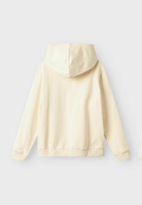 Sudadera con capucha en color crema, hecha de tela suave, con un corte holgado, puños y cintura acanalados. La vista trasera muestra una textura suave.