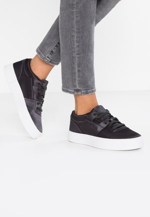 Sneaker nere con tomaia in tessuto testurizzato, lacci coordinati e suola a piattaforma bianca. Presentano un logo sul pannello laterale e dettagli cuciti.