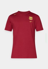 Punane lühikeste varrukatega T-särk, mis on valmistatud puuvillast, särk on kaunistatud kollase Nike logoga ja Barcelona klubi embleemiga rinnal. Sujuv tekstuur.