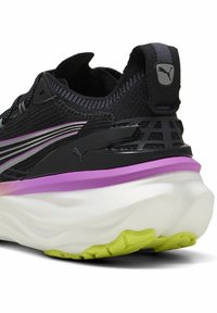 Schwarzer Laufschuh mit strukturiertem Obermaterial, lila Zwischensohle und weißer, gepolsterter Sohle. Verfügt über Puma-Branding und einen gemusterten Fersenakzent.