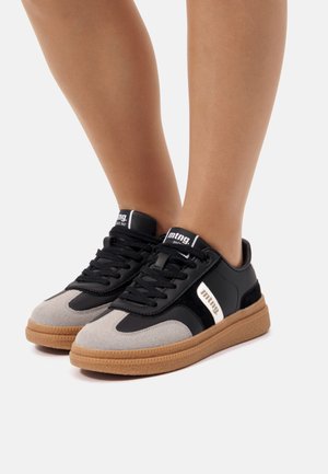 Baskets avec un bout en suede gris, des côtés en cuir noir et une semelle en caoutchouc couleur gomme. Fermeture à lacets et détail de logo sur le côté.