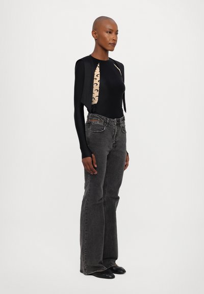Body a maniche lunghe nero con pannello laterale beige a fantasia, abbinato a jeans grigi a campana. Modella che indossa calzature nere.