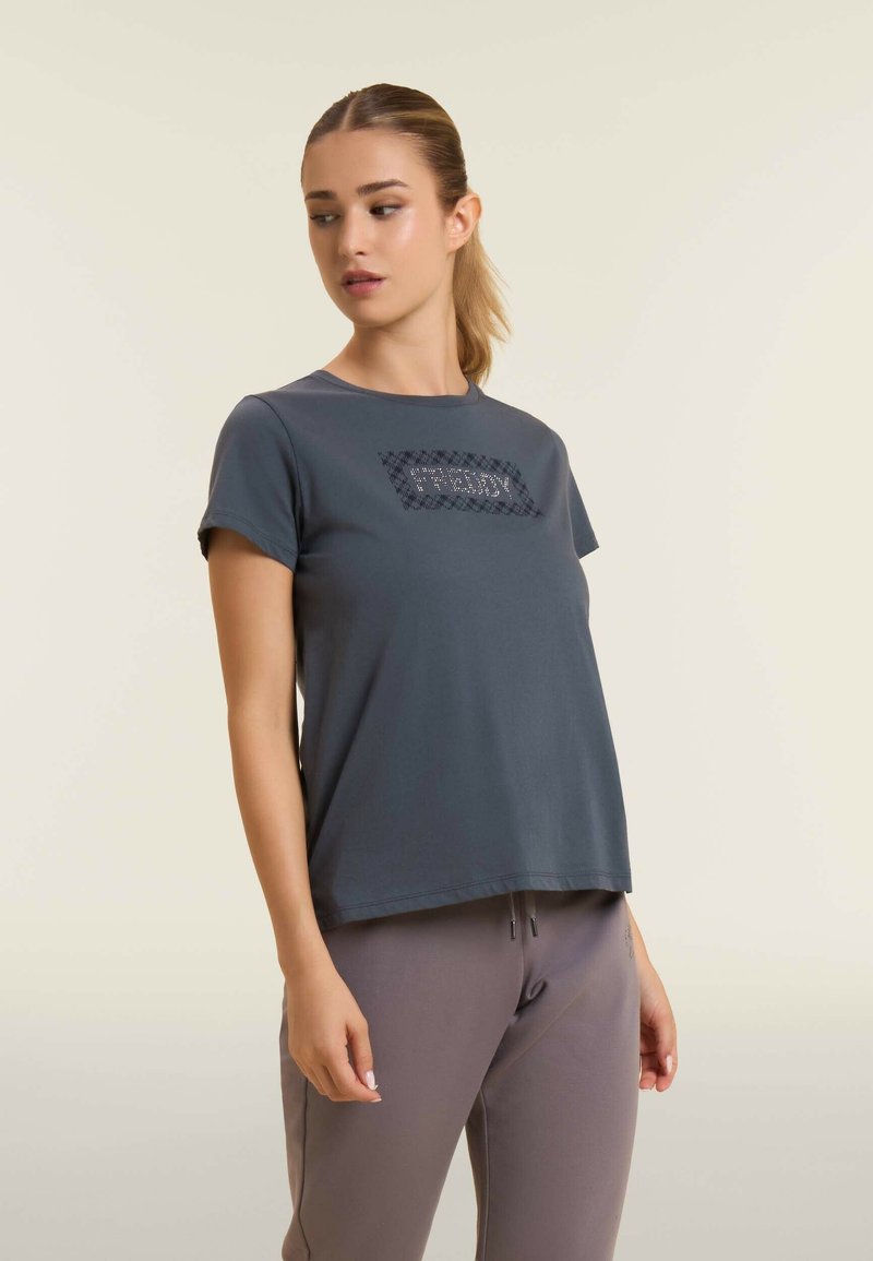 Camiseta gris de manga corta hecha de un tejido suave, con un diseño rectangular texturizado en la parte frontal. Cuello redondo, corte relajado.