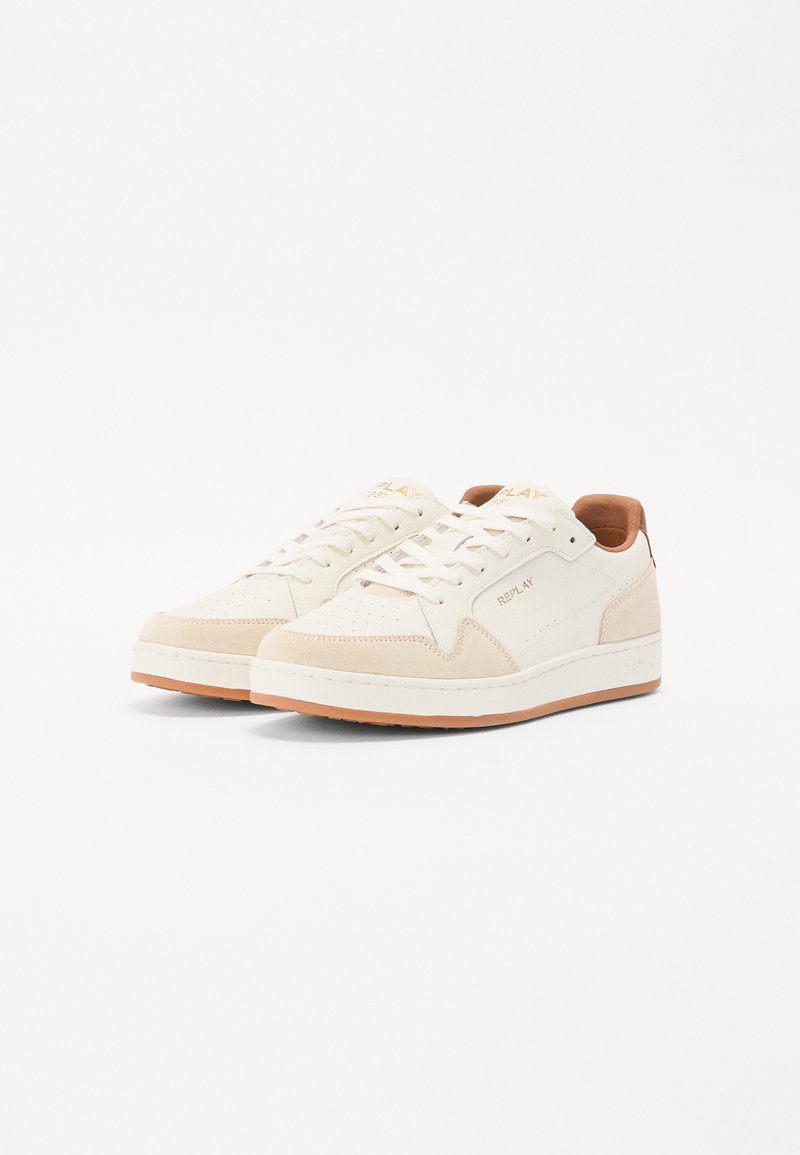 Weiße Ledersneaker mit cremefarbenen Wildlederakzenten, runder Zehenform, Perforierungen, flachen weißen Sohlen und einer hellbraunen Fersenschlaufe. Das "REPLAY"-Logo ist sichtbar.
