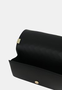 Clutch bag in pelle nera con superficie liscia e chiusura a pattina. Presenta un accento in metallo dorato vicino al gancio. Interno spazioso.