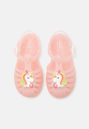 Para przezroczystych, różowych sandałów dziecięcych z brokatem i kolorową ozdobą jednorożca na każdym.