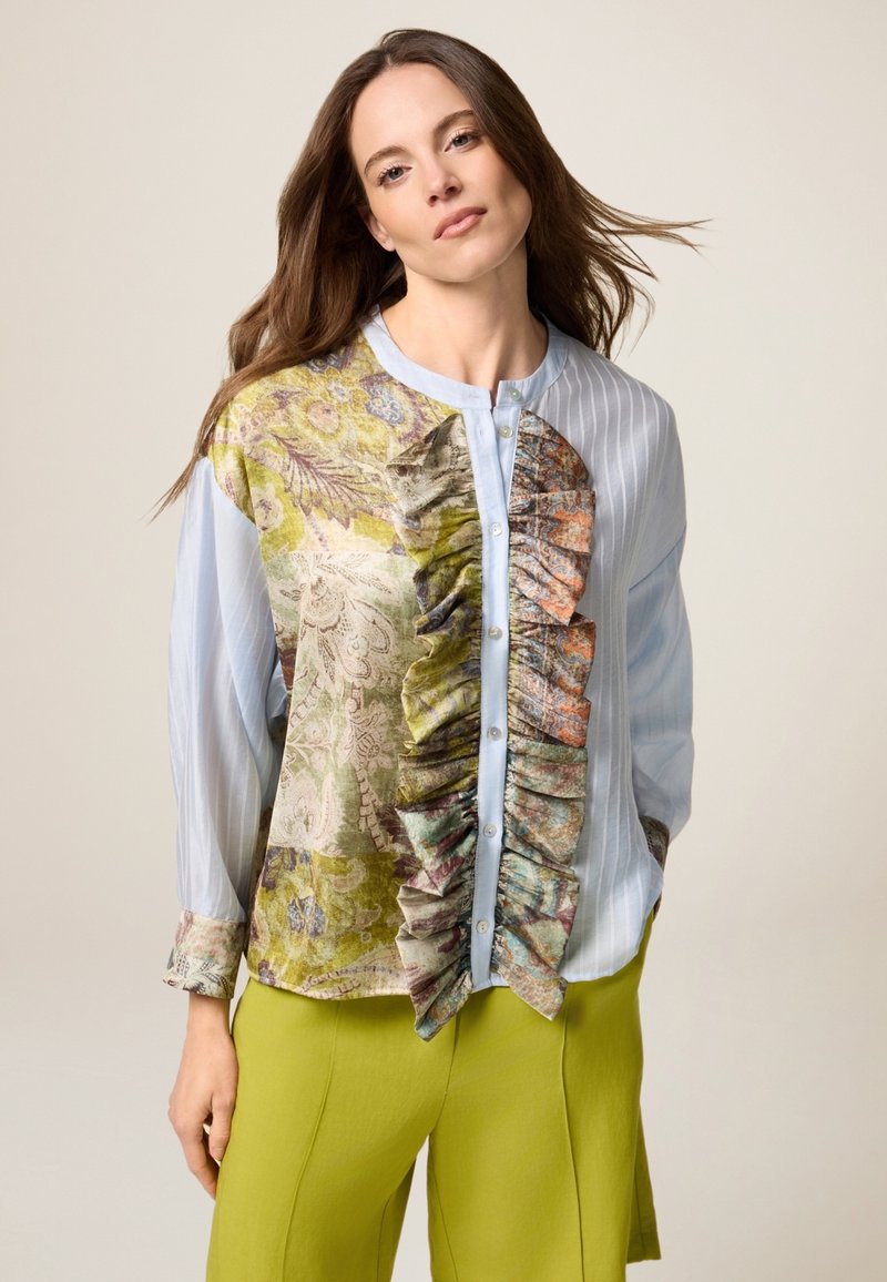 Camicia button-up con una parte anteriore multicolore decorata con rouches, tonalità di blu chiaro e verde, e righe verticali sulle maniche lunghe.