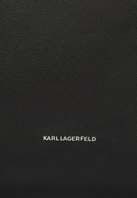 Produit en cuir texturé noir arborant un logo argenté "KARL LAGERFELD" bien en vue. Design simple et raffiné avec des accents minimaux.
